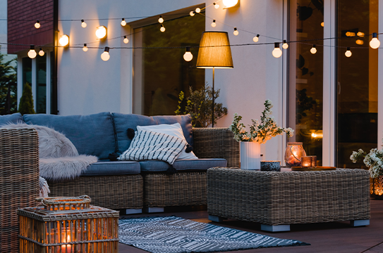 A wicker outdoor furniture set is beautifully framed by fairy lights used as accent lighting.